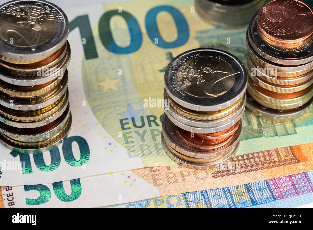 Euro valuta, cento euro fattura. Accatastato euro monete in cima Foto Stock