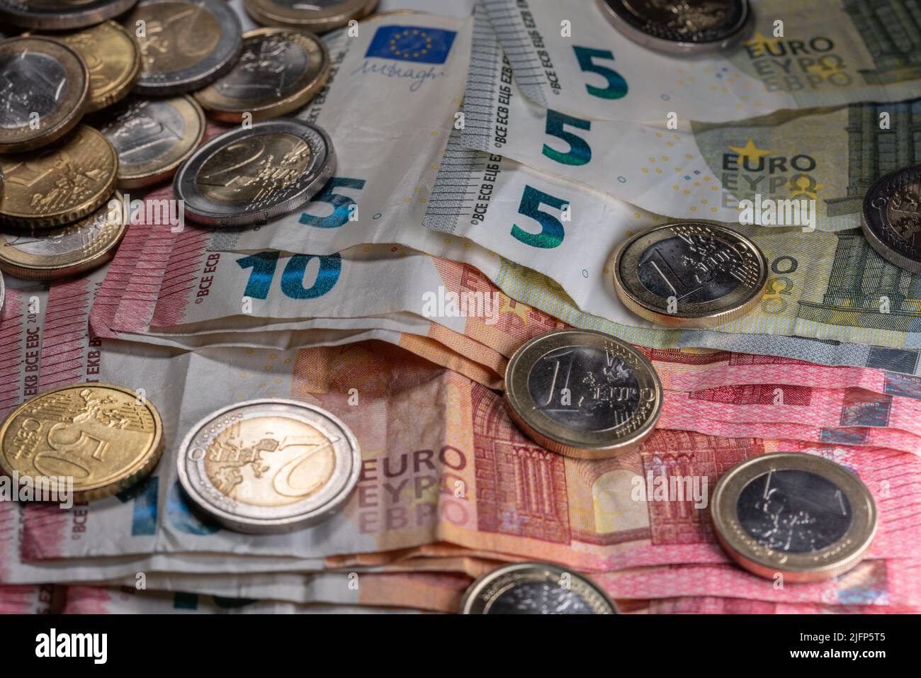 Pila di dieci e cinque euro fatture con monete sopra esso. Denaro per stimoli economici Foto Stock