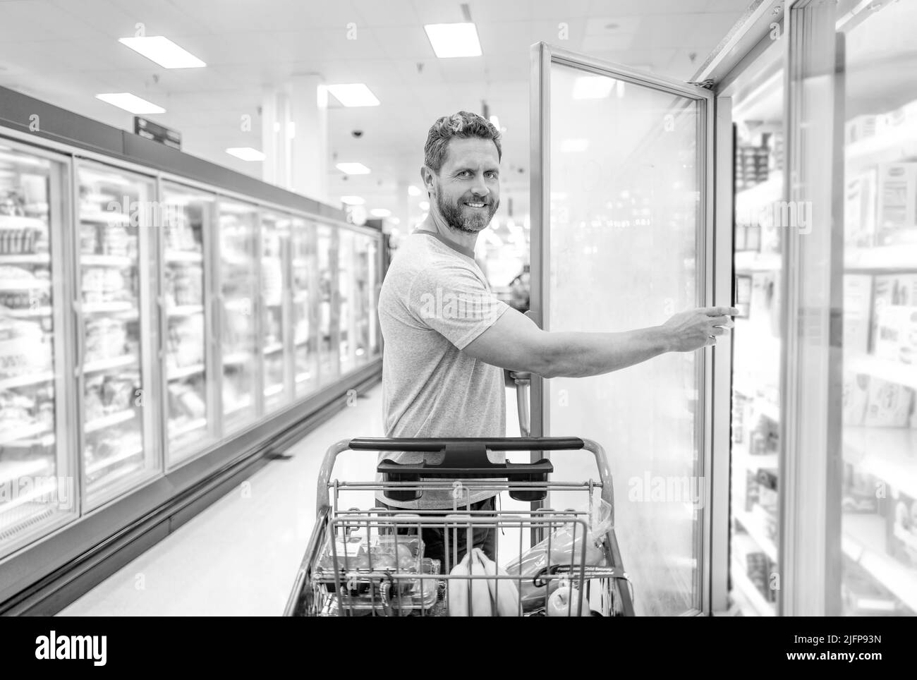 uomo felice con carrello di acquisto di cibo al negozio di alimentari, shopping Foto Stock