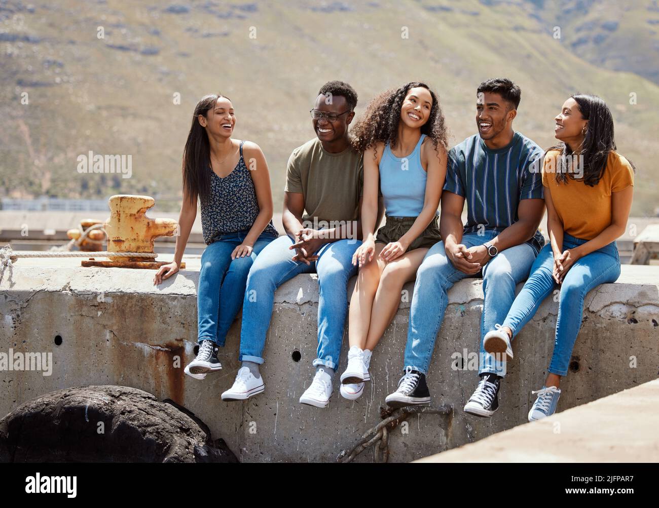 Nessuna amicizia è un incidente. Foto di un gruppo di giovani amici seduti insieme su un molo. Foto Stock