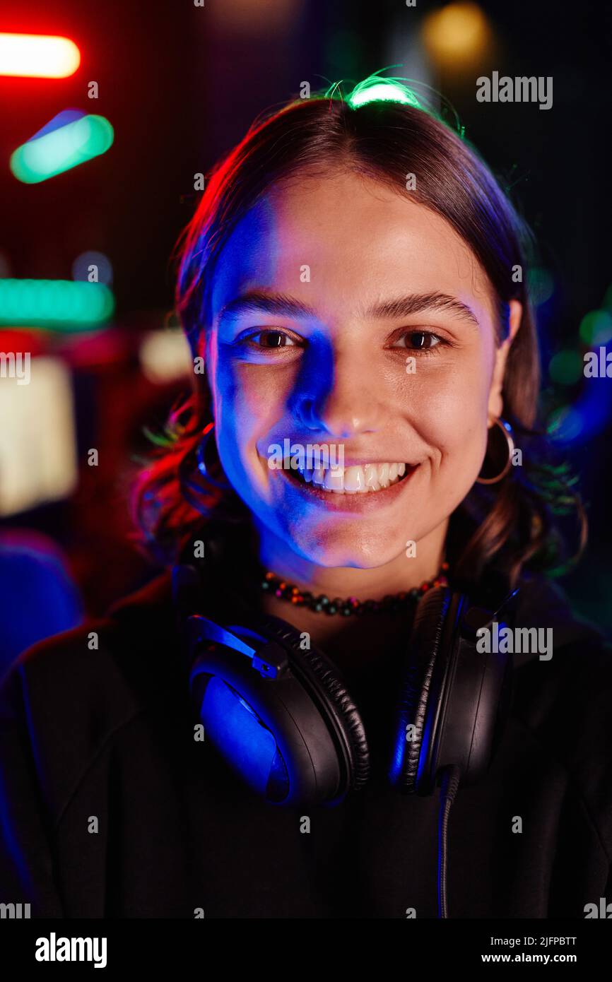 Ritratto di closeup verticale della giovane donna sulla squadra di cyber sport sorridendo alla macchina fotografica allegra illuminata da luce al neon Foto Stock