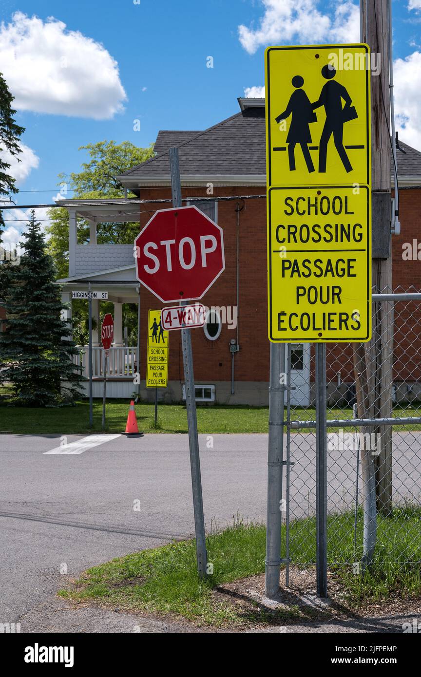 Cartello di attraversamento della scuola bilingue accanto a un segnale di stop Foto Stock