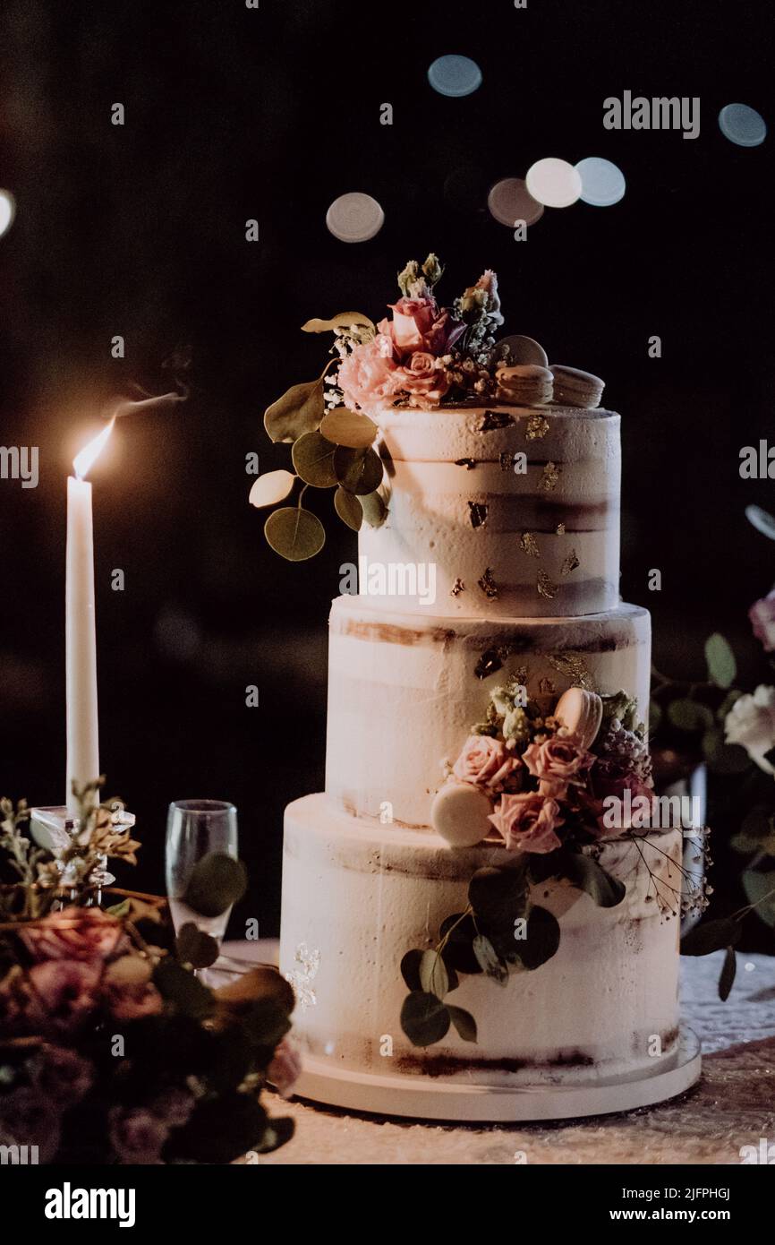 Una torta nuziale con decorazioni e una candela illuminata su un tavolo  esterno Foto stock - Alamy