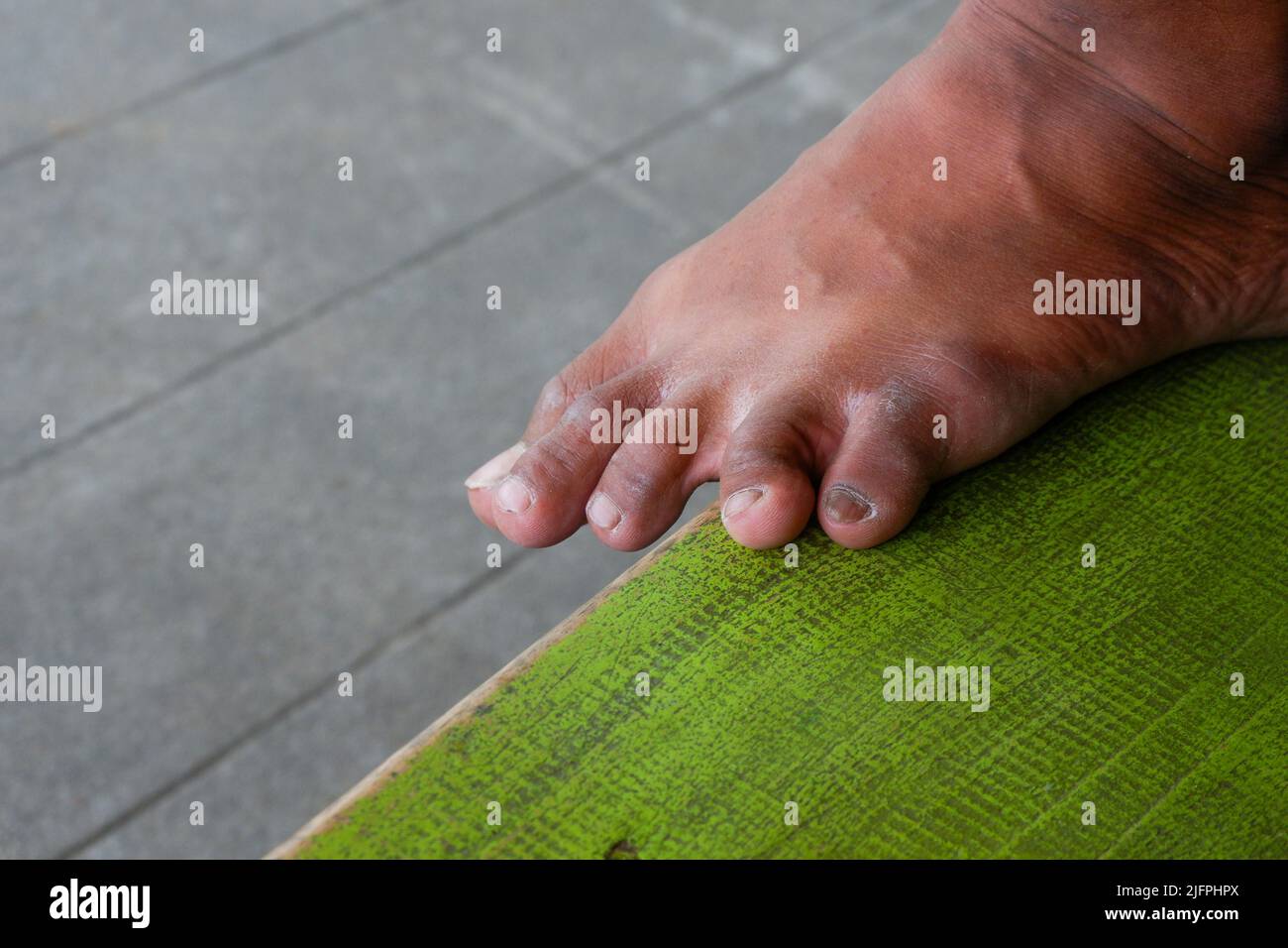 dita dei piedi asiatiche sporche su asse di legno verde Foto Stock