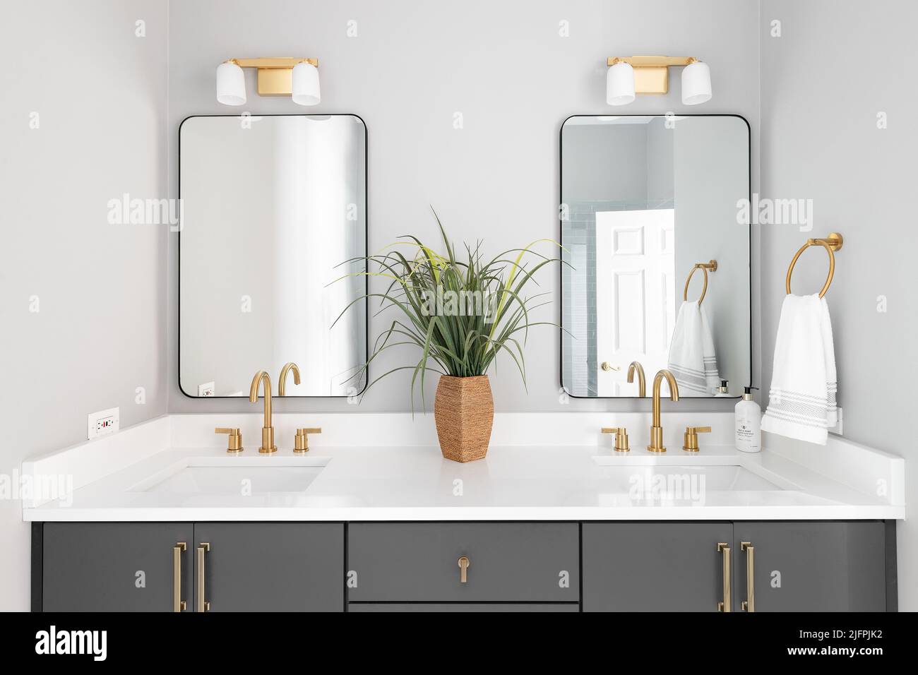 Bagno con lavandino grigio, luci dorate e rubinetti e ripiano in marmo bianco. Foto Stock