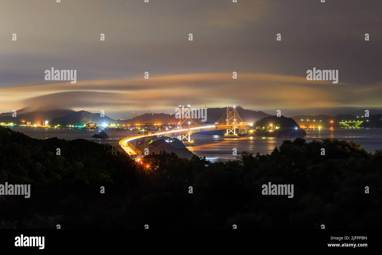 Vista notturna del traffico e della nebbia che si muovono sul ponte sospeso Foto Stock