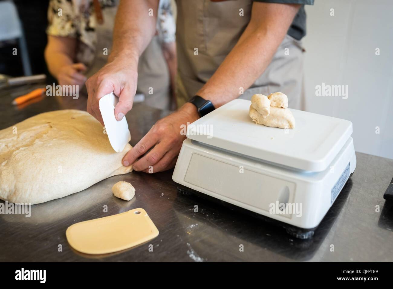Il processo di preparazione del pane. Dividendo l'impasto di grano in pezzi per ciambelle. Vista frontale. Foto Stock