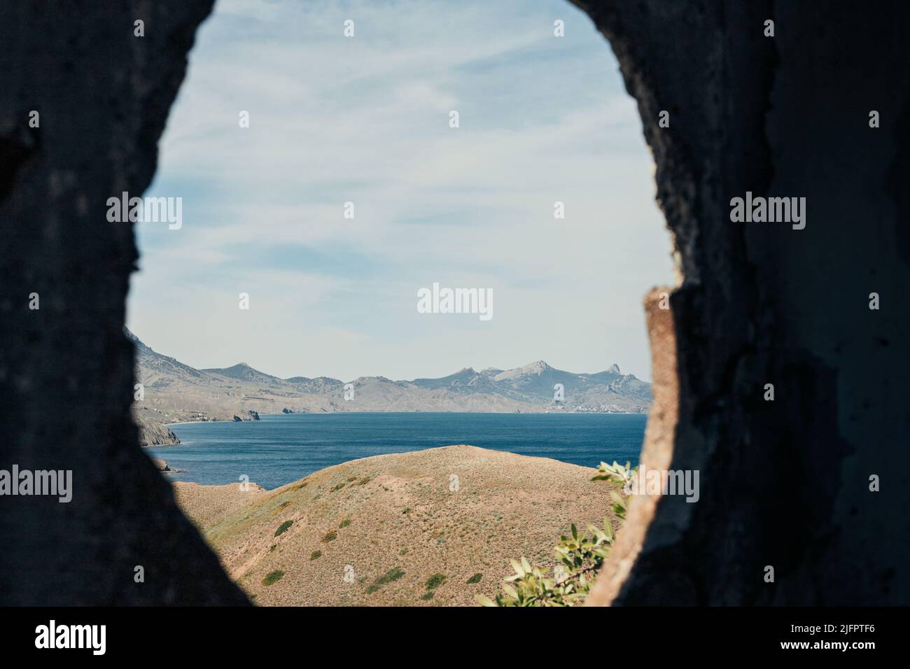 Il mare e le rocce sulla costa meridionale. Crimea, paesaggio in una giornata di sole. Vista attraverso un foro nella parete. Vista frontale. Foto Stock