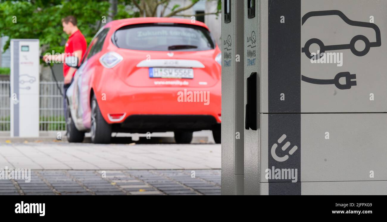 Hannover, Germania. 01st luglio 2022. Un dipendente di Enercity è in piedi con un'auto elettrica accanto alle colonne di ricarica in un nuovo parcheggio di ricarica (posto scena durante l'opportunità di foto). L'utility regionale Enercity sta aprendo un parco di ricarica per le auto elettriche nel distretto List di Hannover. I residenti hanno accesso a 84 punti di ricarica con una potenza di 22 kW e a sei punti di ricarica rapida con una potenza massima di 150 kW ciascuno. 60 punti di ricarica sono già stati affittati da 30 anni. Credit: Julian Stratenschulte/dpa/Alamy Live News Foto Stock