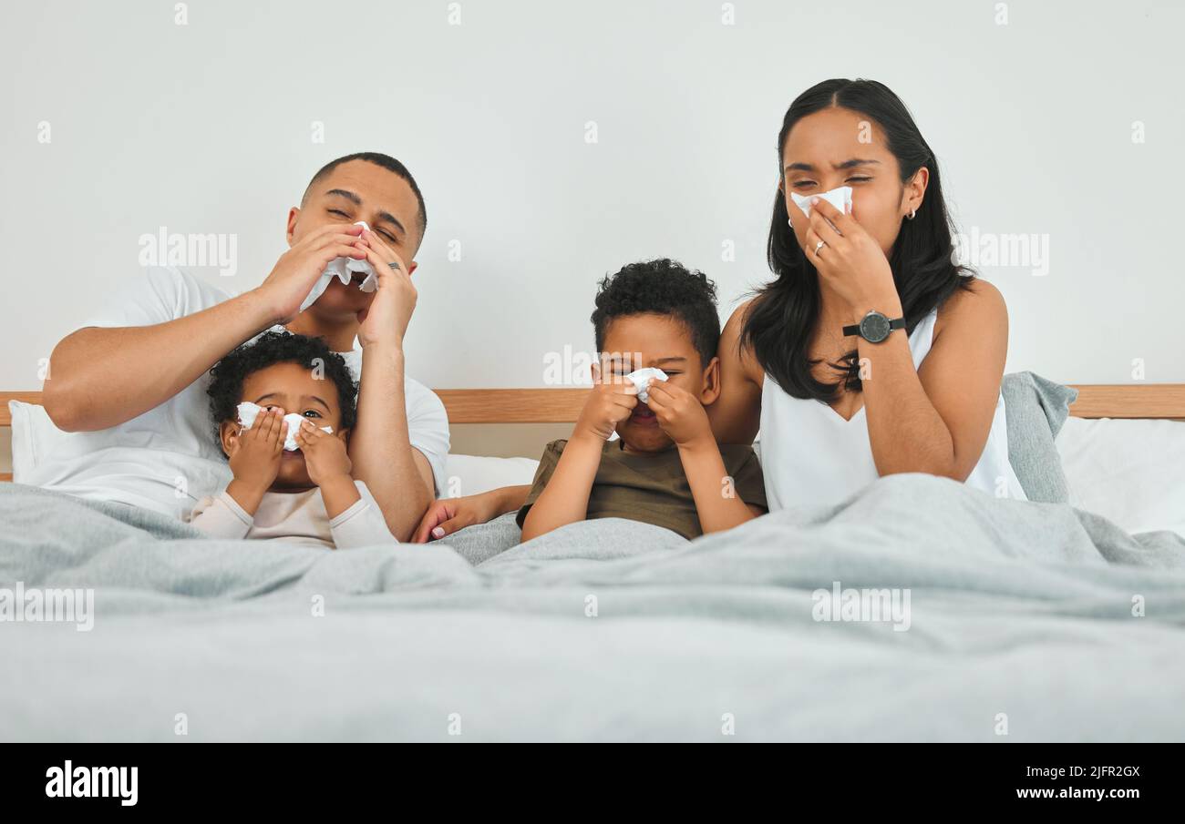 Ora erano tutti malati. Colpo di una famiglia che soffia i loro nasi mentre ammalato a letto a casa. Foto Stock