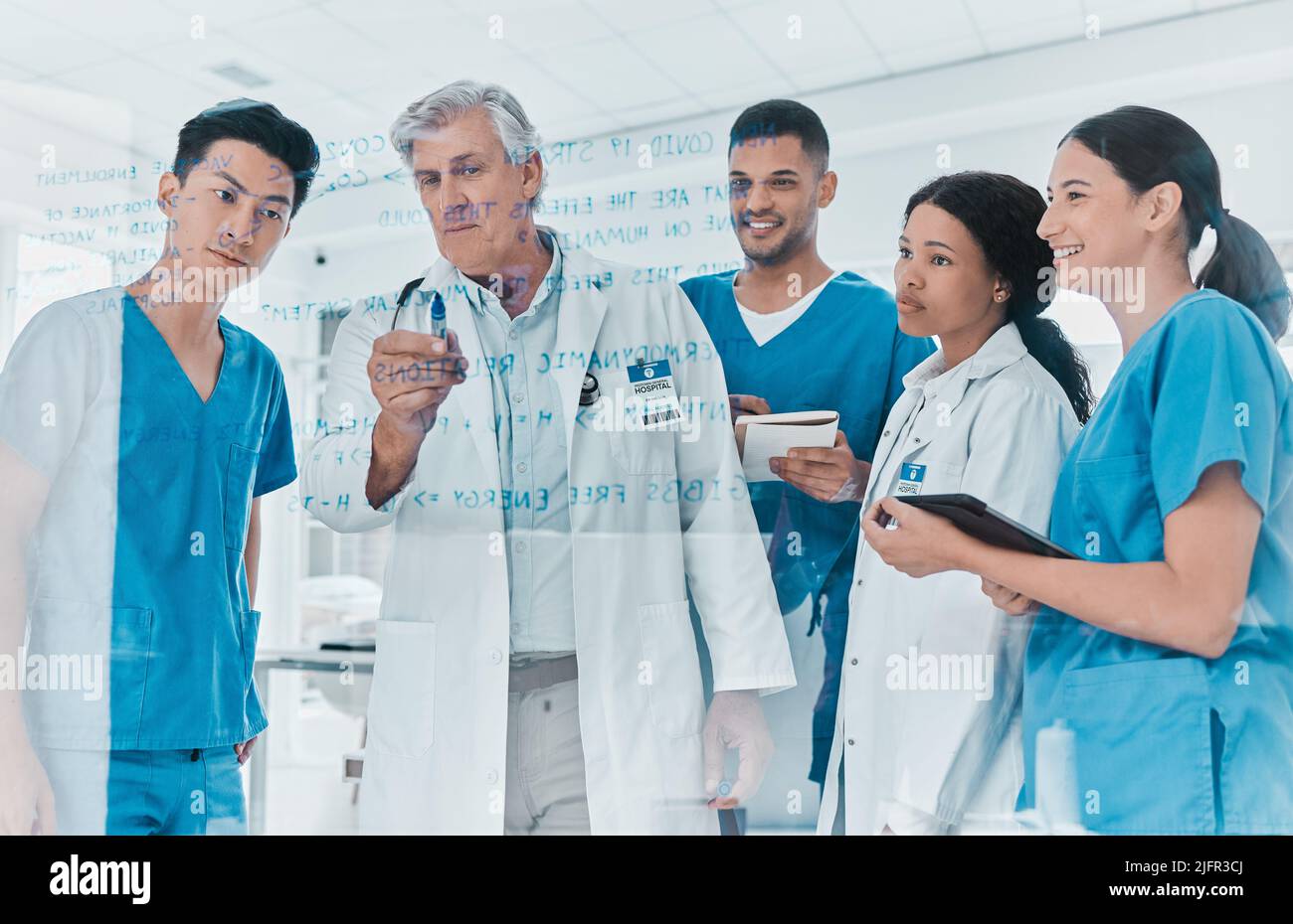 Sviluppo della sanità e della medicina come scienza cooperativa. Shot di un gruppo di medici medici brainstorming con note su una parete di vetro in un Foto Stock