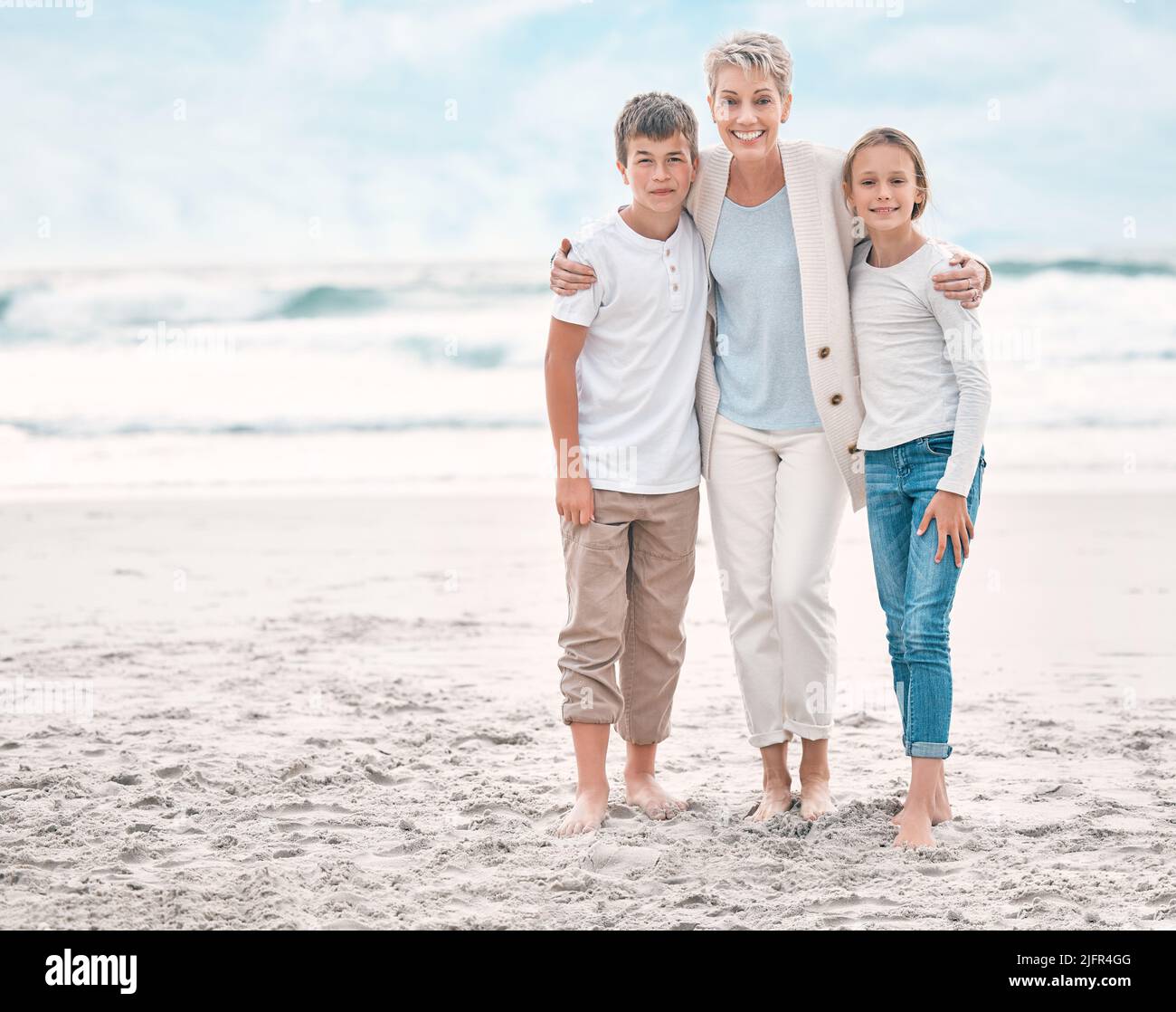 L'illuminazione fa l'immagine. Scatto di una donna matura e dei suoi nipoti che si legano alla spiaggia. Foto Stock