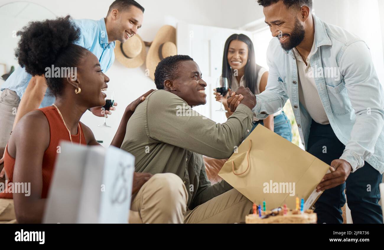Egli passa sempre per me. Scatto di un giovane uomo che apre regali al suo compleanno a casa. Foto Stock
