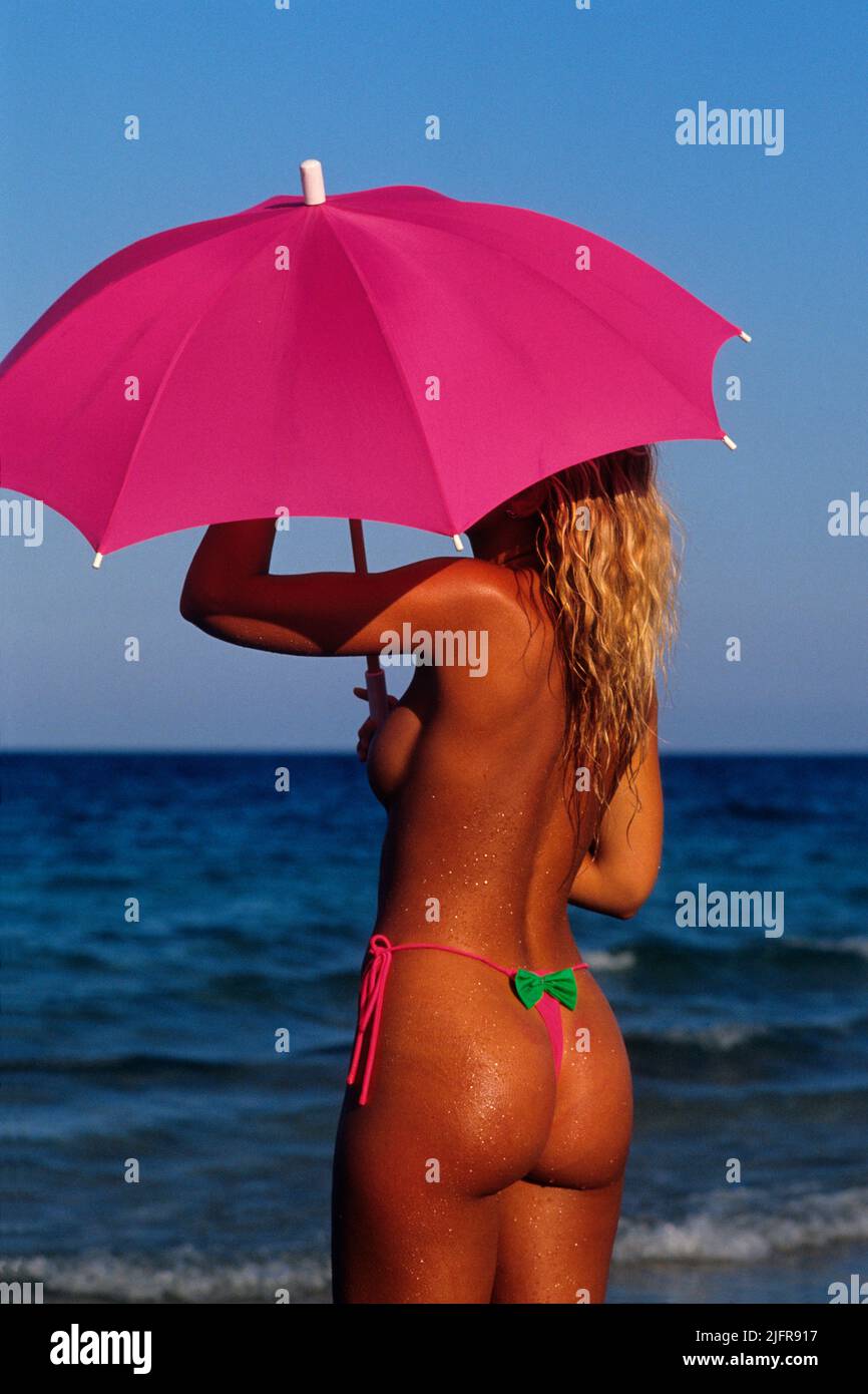 Giovane donna bionda capelli si siedono sulla spiaggia posteriore fotocamera fronte mare sfondo Foto Stock