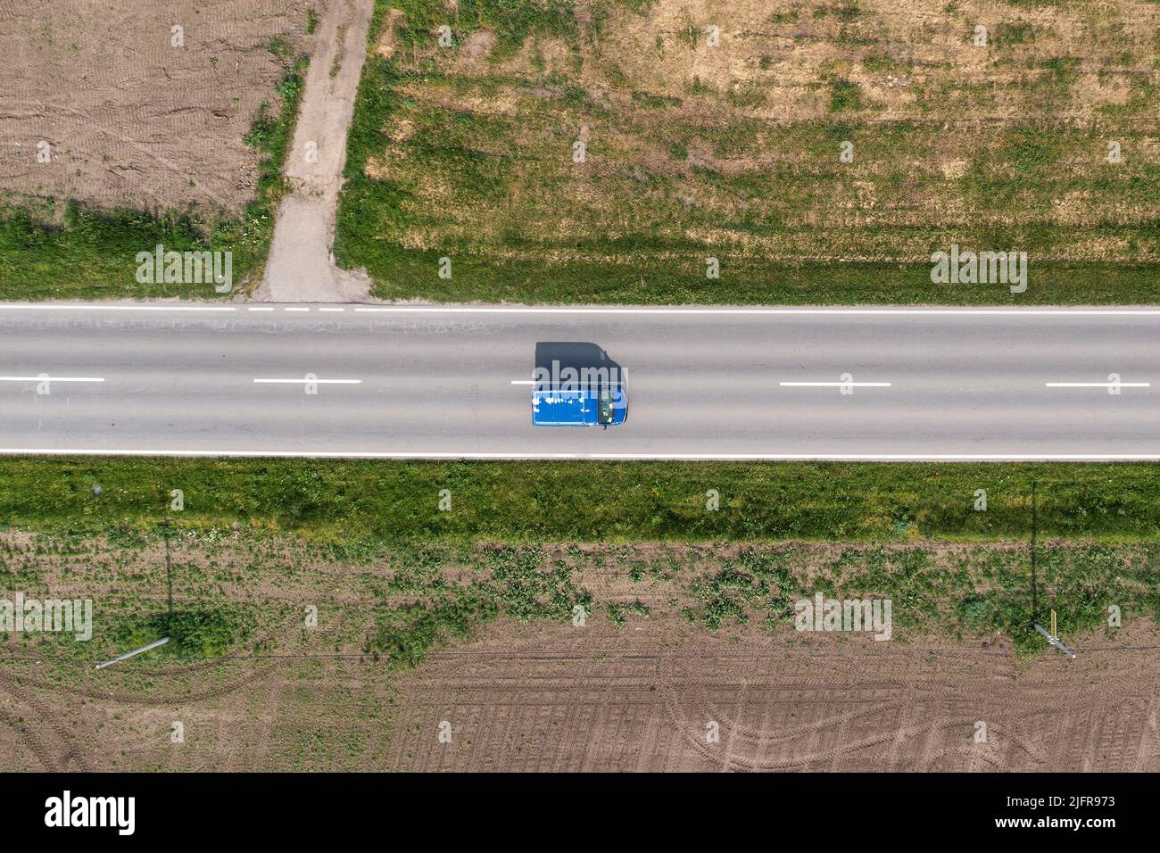 Vista dall'alto del vecchio furgone blu sull'autostrada attraverso la campagna nella soleggiata primavera Foto Stock