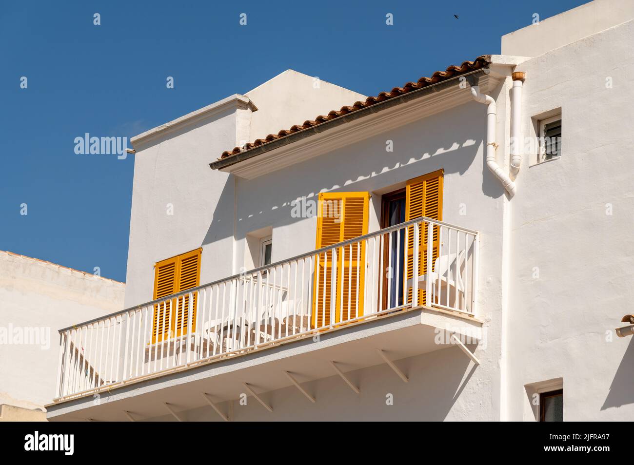 Cala Ratjada, Maiorca, Spagna; 25th giugno 2022: Casa bianca con persiane gialle sul lungomare di Cala Ratjada Foto Stock