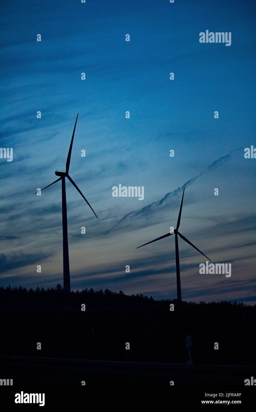Un colpo verticale di silhouette di mulini a vento durante il tramonto - sostenibile clima visivo Foto Stock