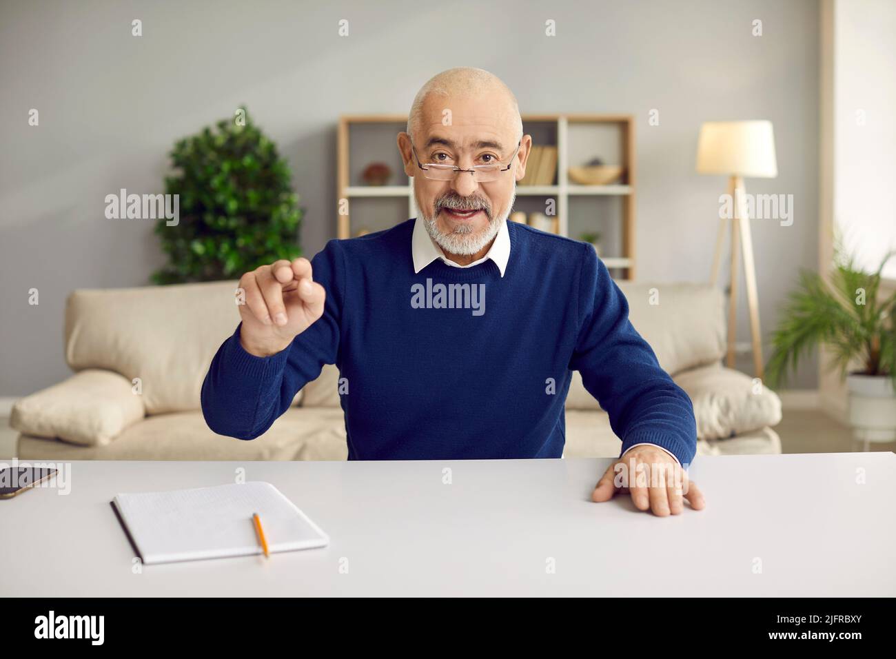 L'uomo anziano esperto parla e conduce il cliente in linea che consiglia mentre si siede nell'ufficio domestico. Foto Stock