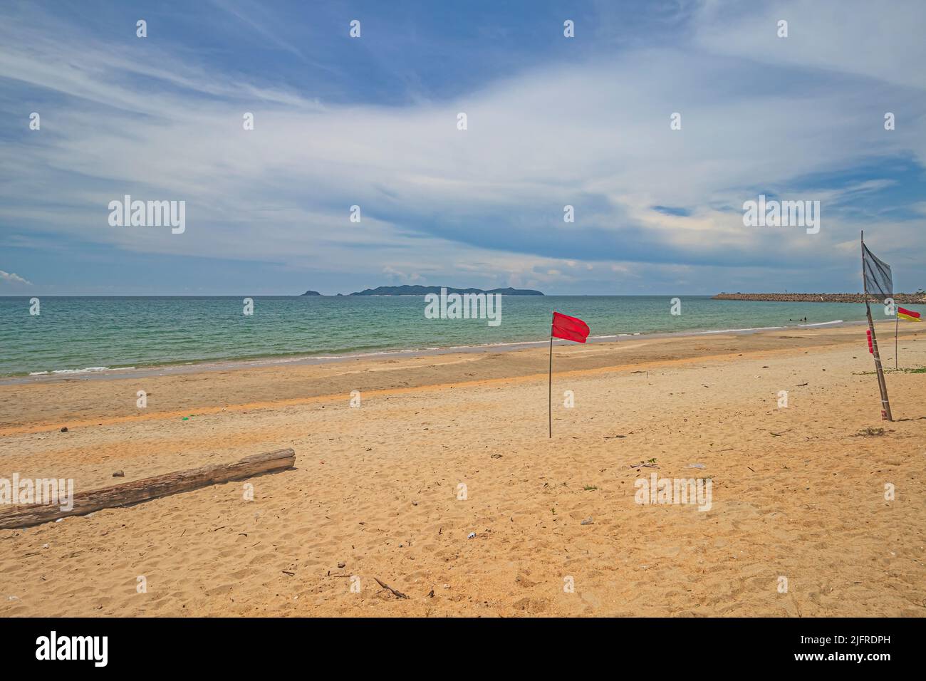 Spiaggia deserta di sabbia dorata con una piccola bandiera arroccata sulla sabbia a Pantai Jambu Bongkok Beach nel distretto di Marang di Terengganu, Malesia. Foto Stock