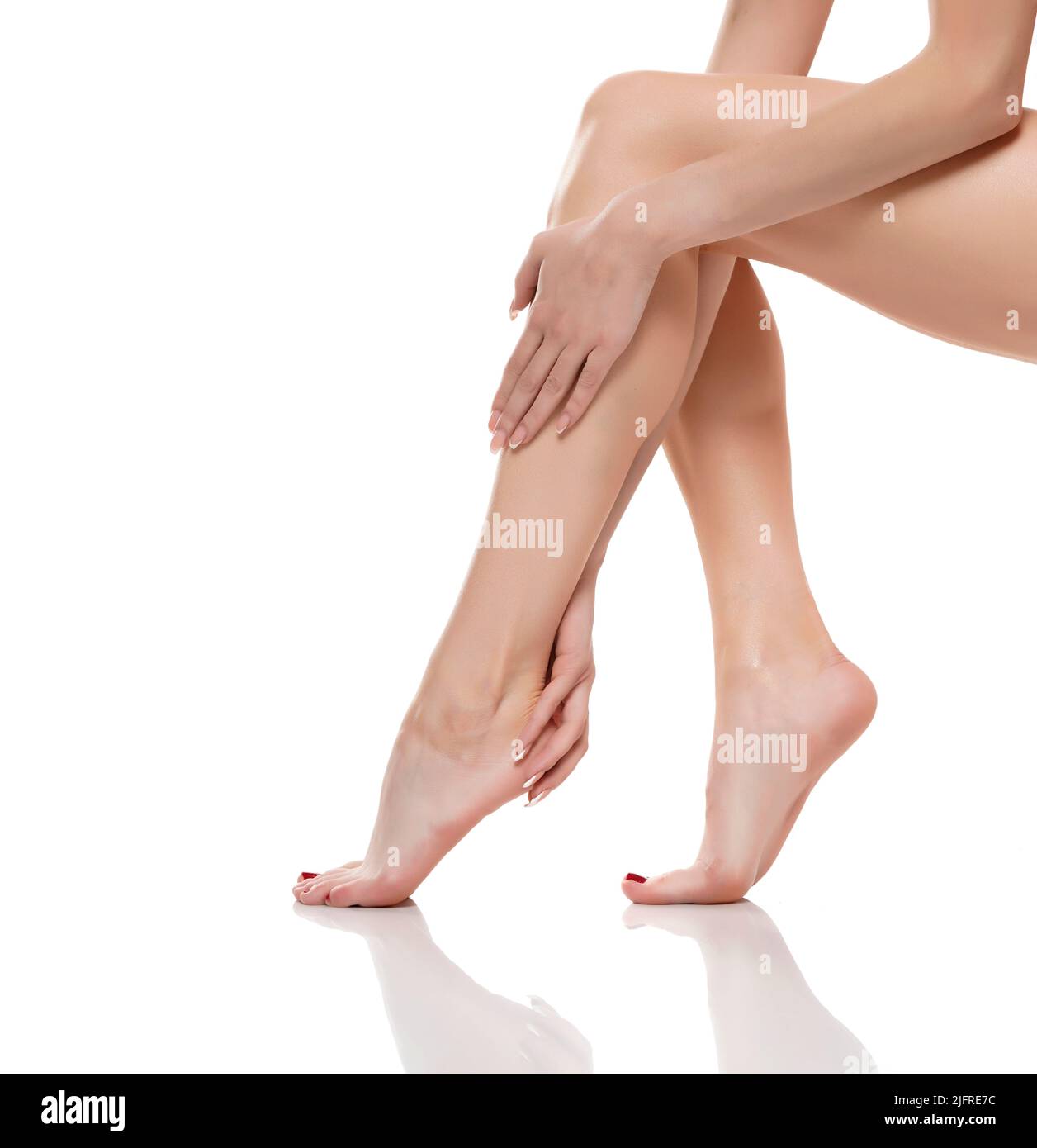 Giovane donna che tocca le gambe lisce lunghe, e che mette su moisturizer dopo la rasatura delle gambe. Foto Stock