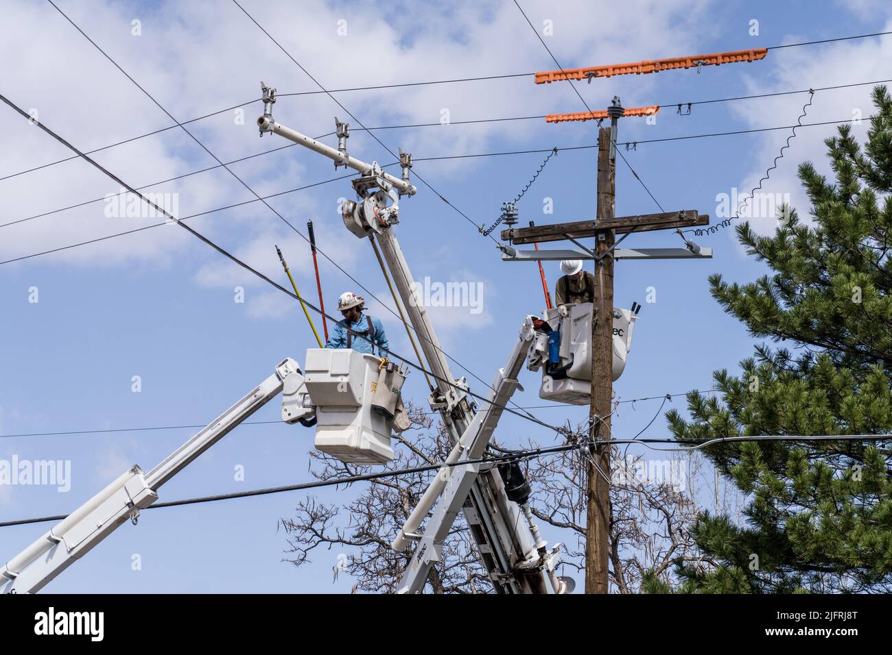 Gli operatori elettrici effettuano la manutenzione su linee di trasmissione elettrica sotto tensione utilizzando speciali precauzioni di sicurezza. Foto Stock