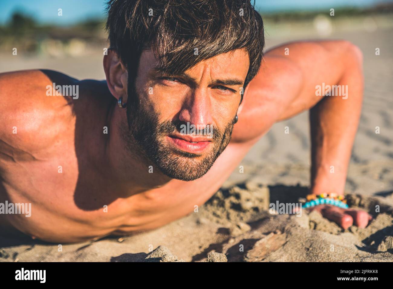 Primo piano ritratto sexy di bel modello maschile topless sulla spiaggia all'alba - Fitness uomo fare push-up sulla spiaggia. Sport e stile di vita attivo. Foto Stock