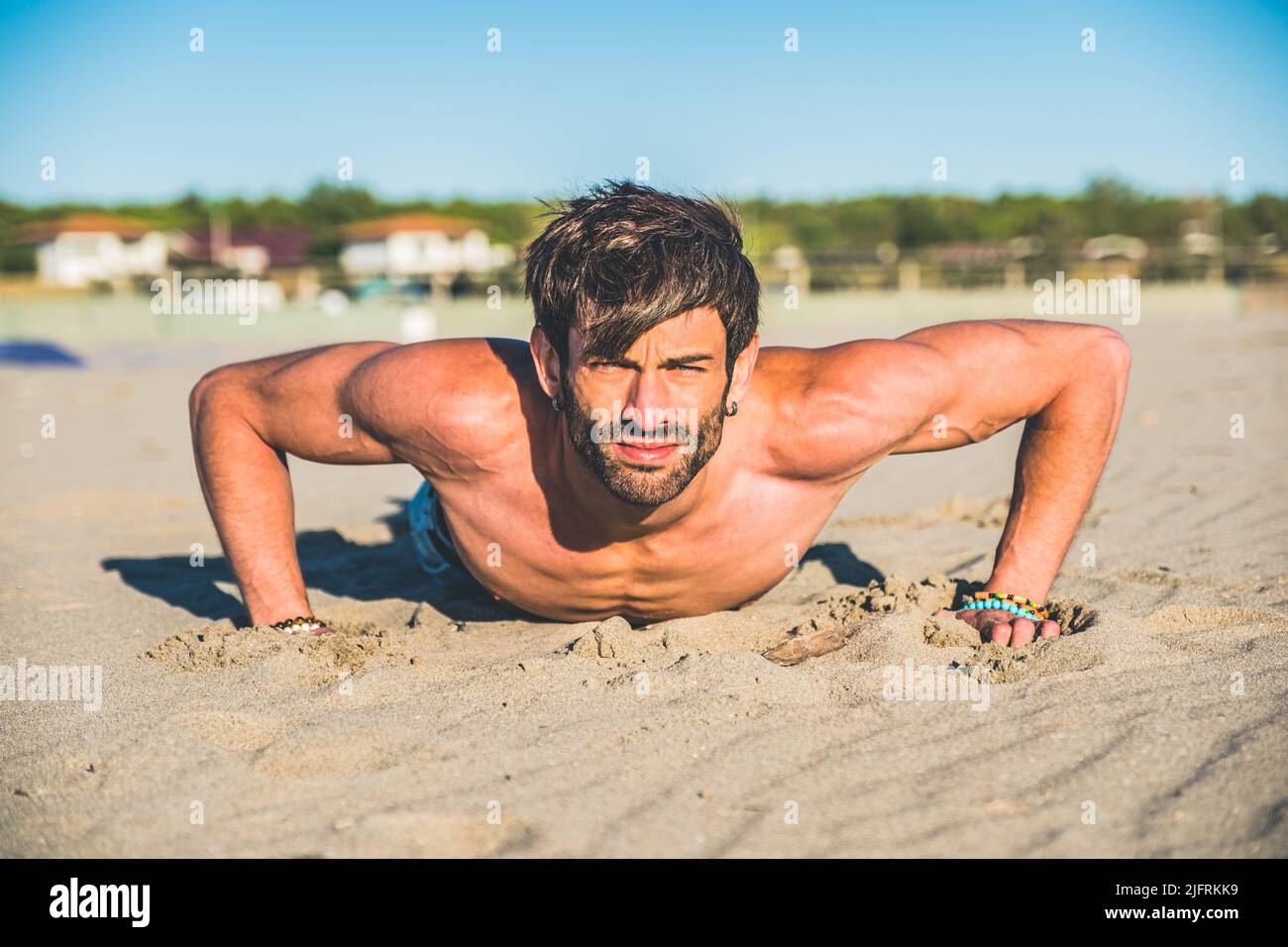 Primo piano ritratto sexy di bel modello maschile topless sulla spiaggia all'alba - Fitness uomo fare push-up sulla spiaggia. Sport e stile di vita attivo. Foto Stock