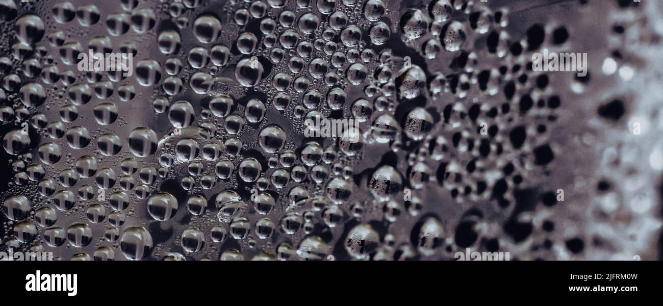 Molte gocce d'acqua pioggia bagnano la condensa del finestrino sul vetro. Sfondo fresco. Texture formate da bolle. Superficie trasparente di raccolta. Foto astratta reale Foto Stock