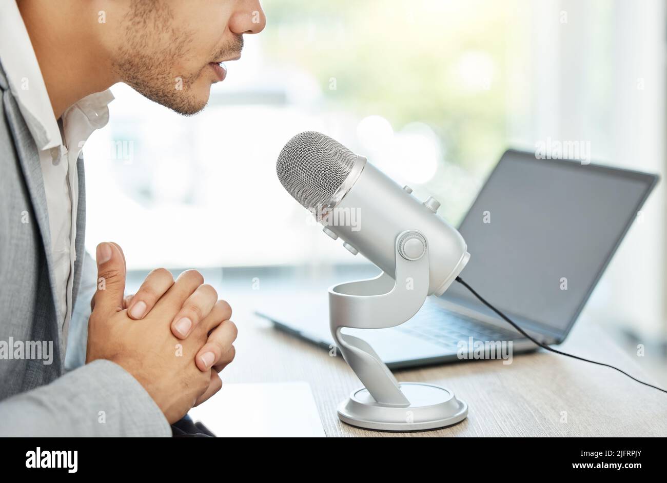 Lascia che la conversazione vada avanti. Primo piano di un uomo d'affari che utilizza un microfono durante una trasmissione in un ufficio. Foto Stock
