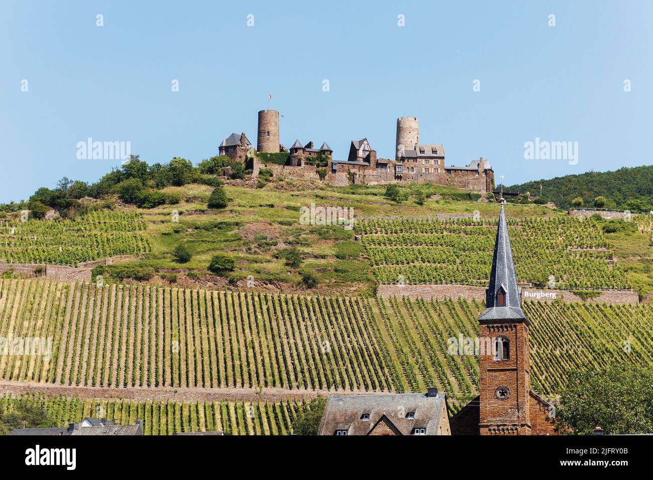 Piccola città tedesca sulle rive del fiume Mosel con un castello sulla collina sopra Foto Stock