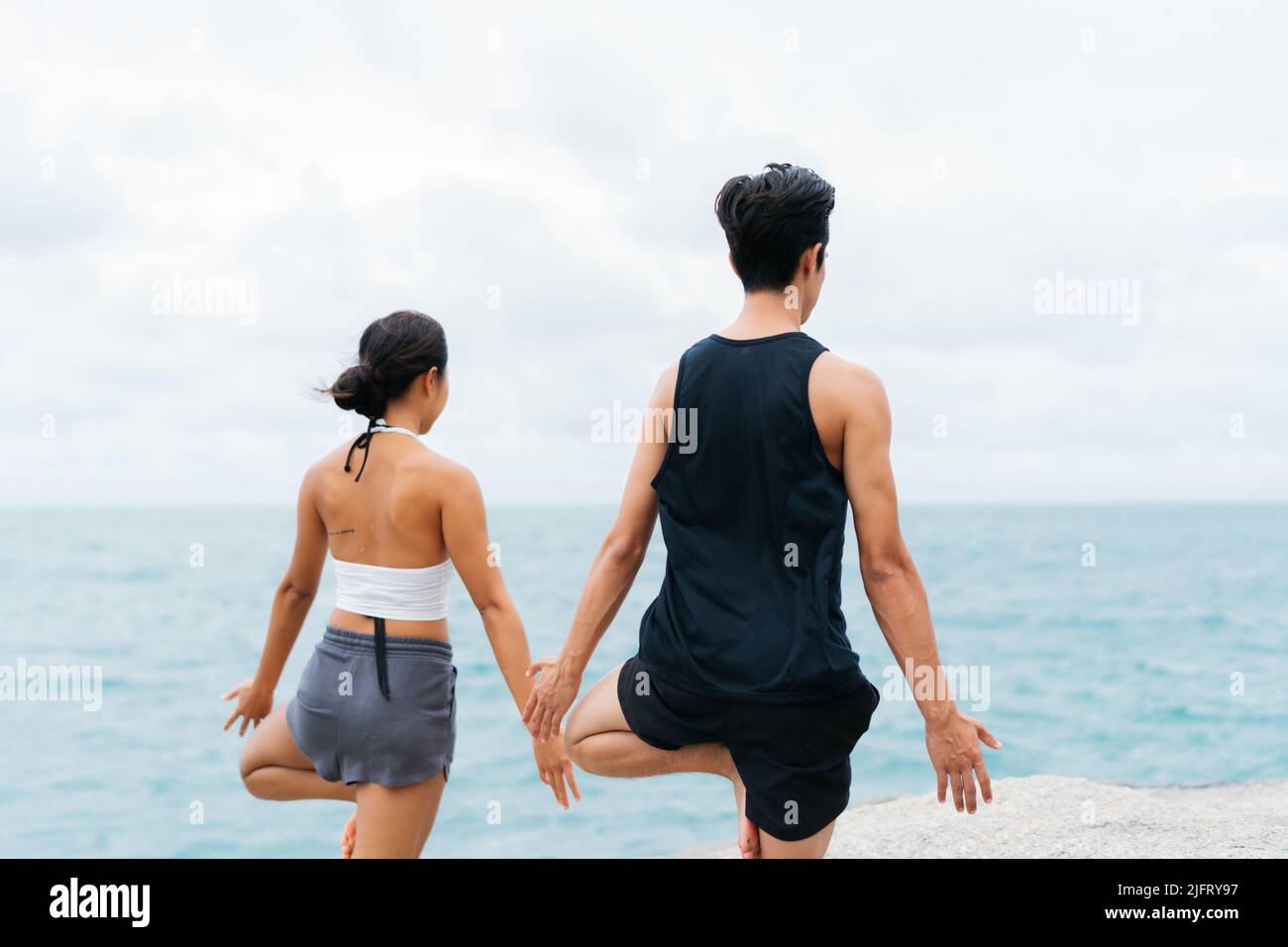 Indietro di pacifica e mentale Asian 30s coppia godendo albero posa yoga in riva al mare. Coppia di uomini e donne è la meditazione e la spiritualità di formazione Foto Stock