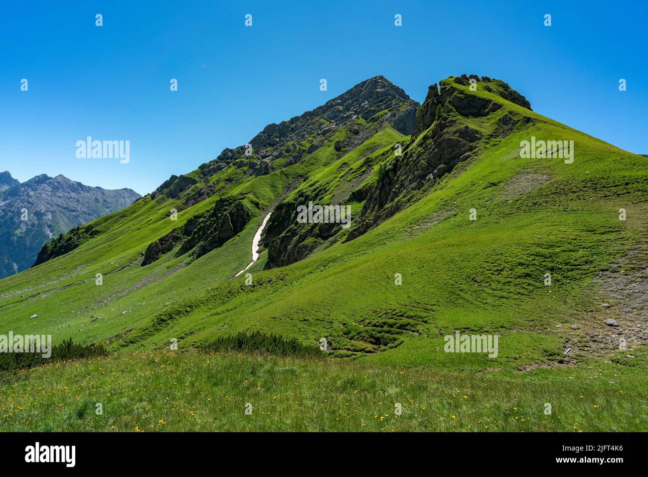 Vista panoramica da Amatschonjoch alla valle di Brand con montagne rocciose e un piccolo campo di neve nei verdi prati alpini Foto Stock