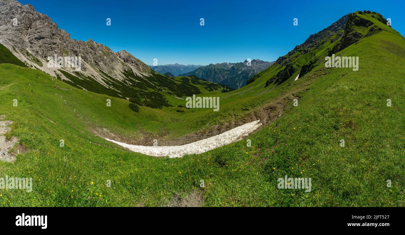 Vista panoramica da Amatschonjoch alla valle di Brand con montagne rocciose e un piccolo campo di neve nei verdi prati alpini Foto Stock