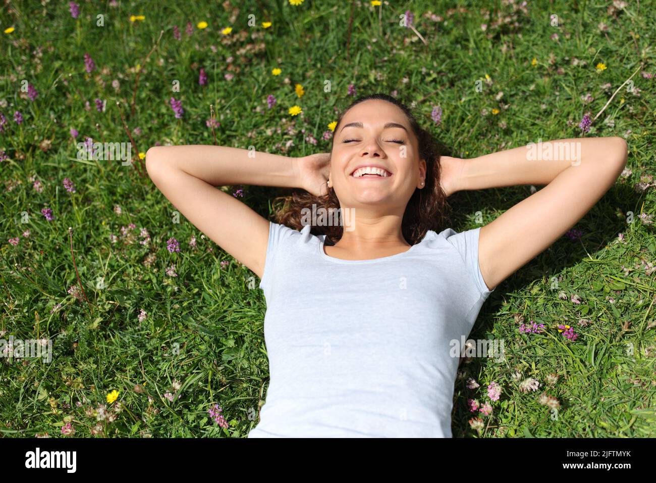 Vista dall'alto di una donna che si rilassa sull'erba e ride in montagna o nel parco Foto Stock