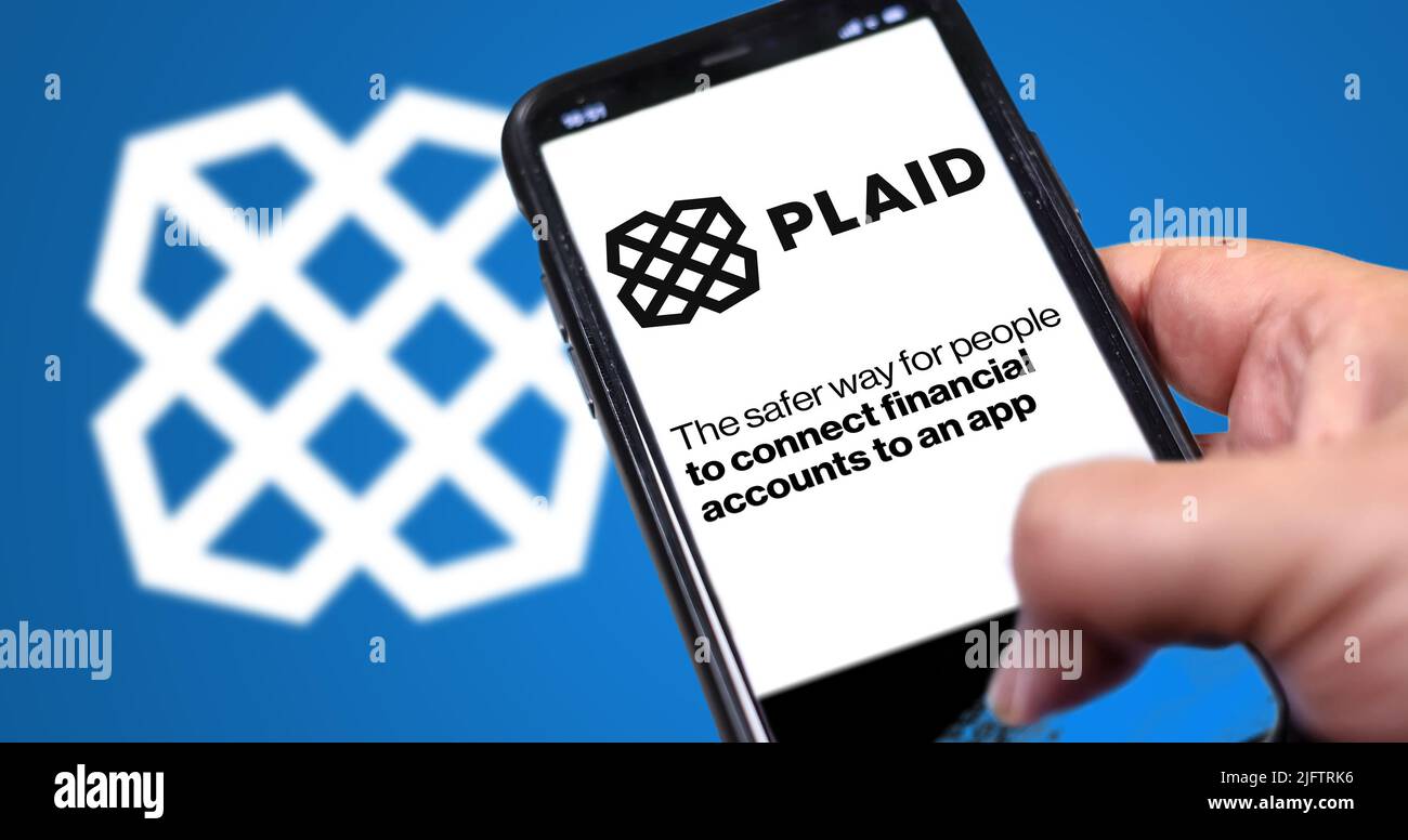 San Francisco, USA, giugno 2022: Tenere un telefono con la home page di Plaid sullo schermo. Logo plaid sfocato su sfondo blu. Plaid è un servizio finanziario Foto Stock
