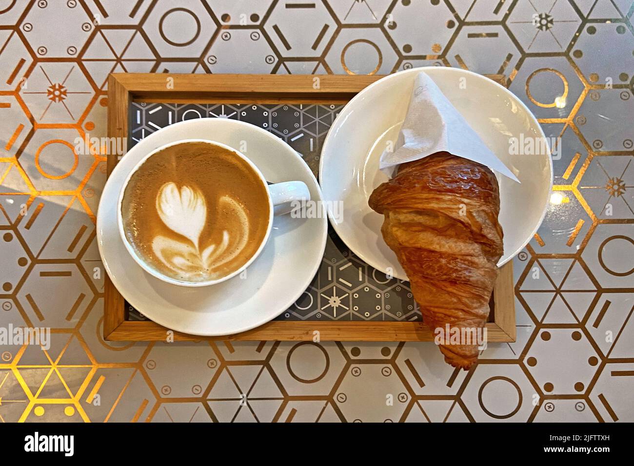 Una tipica colazione italiana: Cappuccino e brioche (croissant) Foto Stock