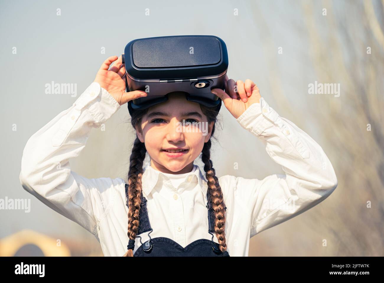 Bambina con occhiali di realtà virtuale. Concetto di tecnologia del futuro - ragazza bella con realtà virtuale all'aperto in un parco Foto Stock