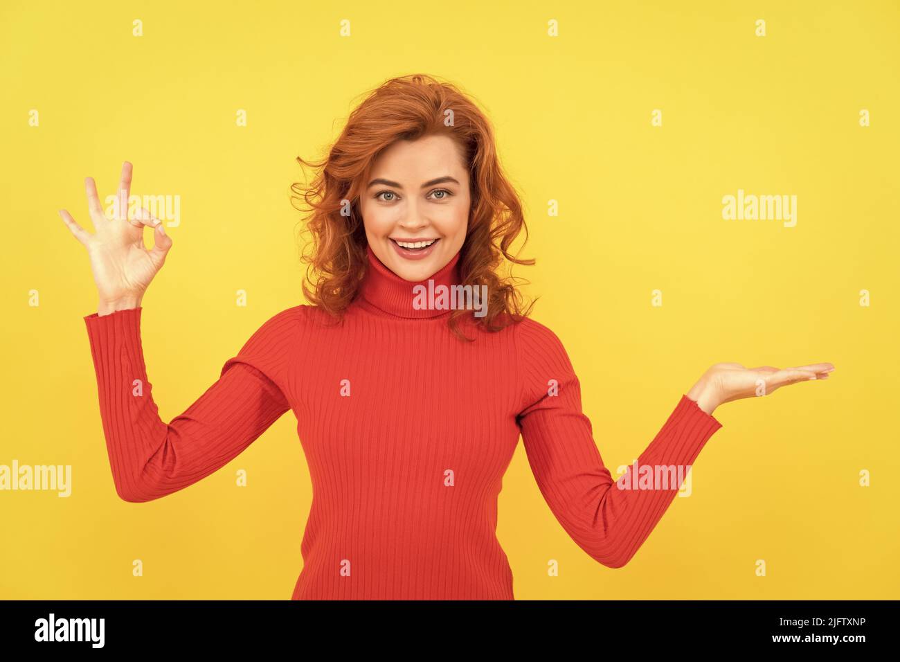 cheerful signora redhead che fa la scelta che presenta il prodotto con lo spazio di copia per la pubblicità, ok Foto Stock