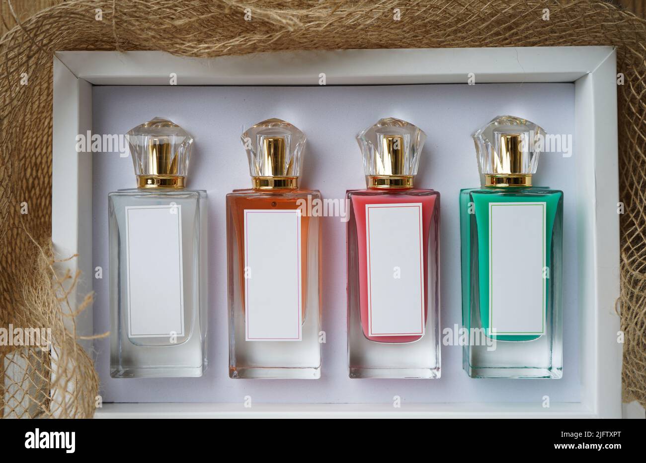 Boccagli in vetro profumato, flaconi cosmetici bianchi su modello di scatola. Con diversi colori di bottiglie rosso, bianco, arancione e verde profumo. Foto Stock