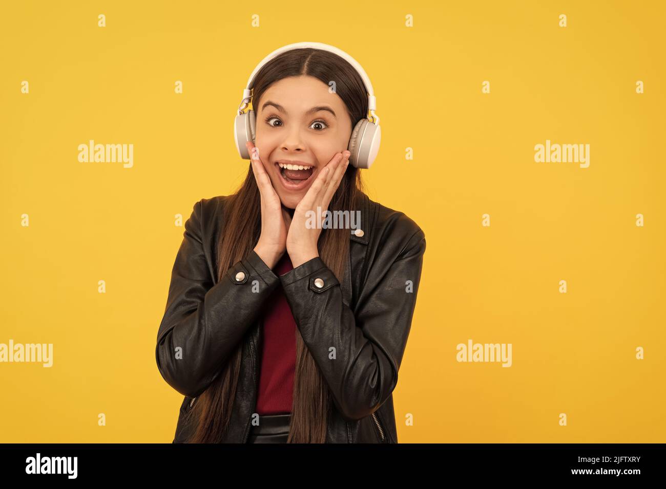 stupito bambino in cuffie su sfondo giallo, musica Foto Stock