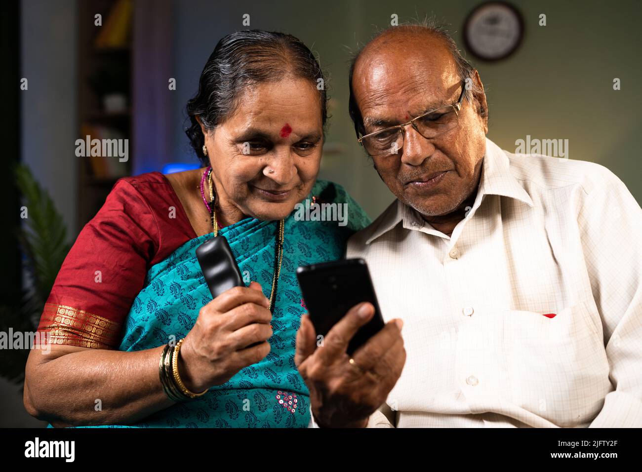 Coppia sorridente felice che usa il telefono cellulare con la moglie che tiene a casa remota - concetti di tecnologia, di convivenza e di stile di vita pensionamento Foto Stock