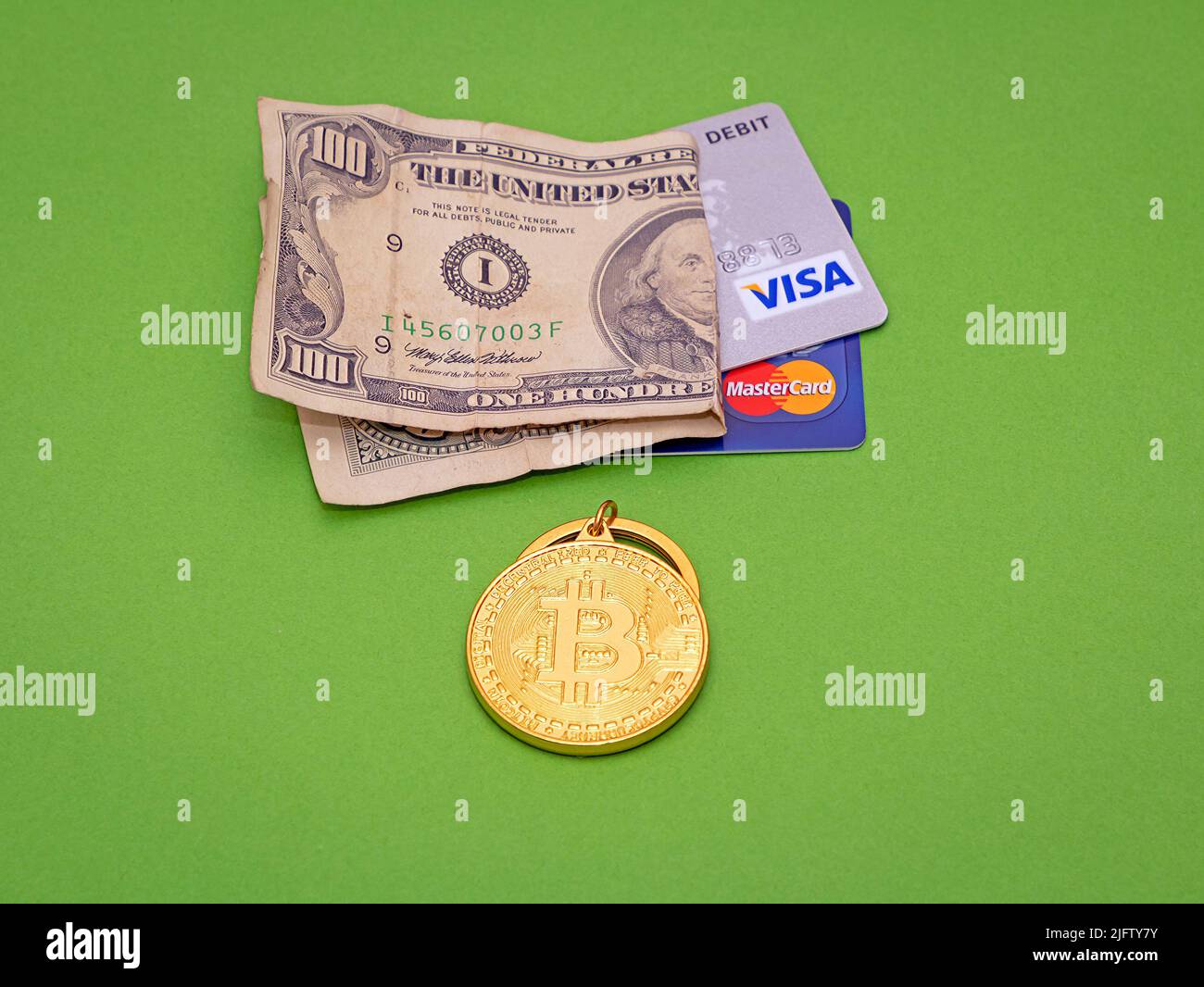 Londra, Regno Unito - 27 maggio 2022: Cripto valuta del bitcoin d'oro con la fattura della carta del dollaro e le carte di credito su sfondo verde. Foto Stock