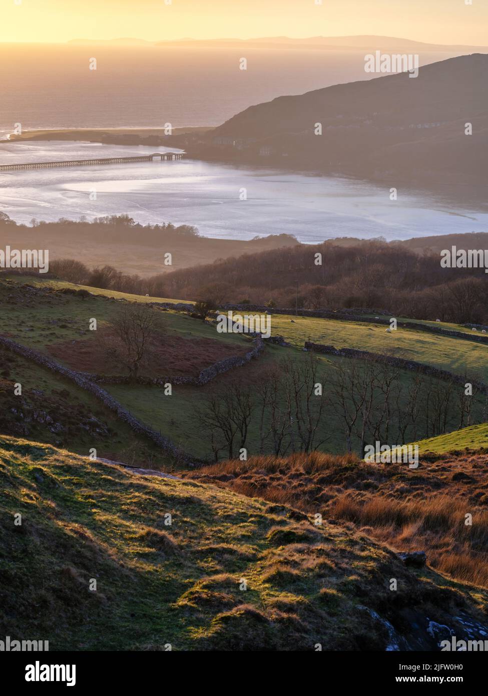 Guardando attraverso la campagna gallese verso la città costiera di Barmouth al tramonto, Gwynedd, Galles del Nord Foto Stock