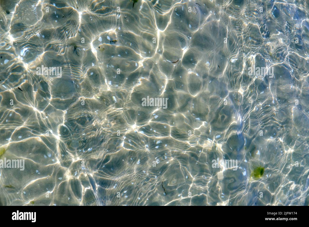 Acqua limpida sulla spiaggia in una giornata estiva con spazio per fotocopie. Vista dall'alto della calma bassa marea del mare ondeggiare durante la primavera. Primo piano del sole luminoso riflesso splendente Foto Stock