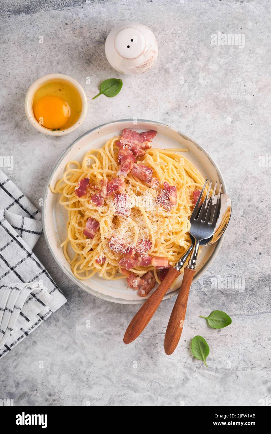 Carbonara pasta. Spaghetti con pancetta, uova, parmigiano e salsa cremosa su fondo di vecchio tavolo grigio in cemento. Cucina tradizionale italiana e. Foto Stock