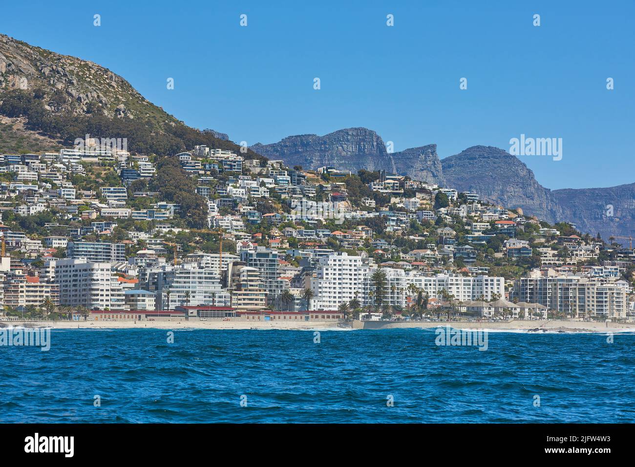 Panorama con le nuvole, il cielo blu e gli eleganti appartamenti dell'hotel sullo sfondo. Sea Point con i dodici Apostoli e Table Mountain Foto Stock