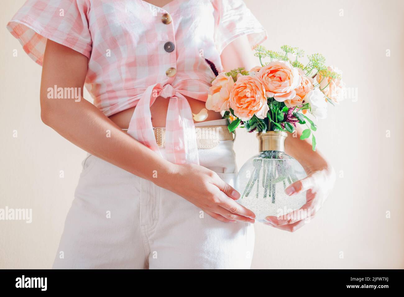 Giovane donna in vaso con bouquet di fiori freschi. Composizione floreale con rose arancioni Signora di Shallott Foto Stock
