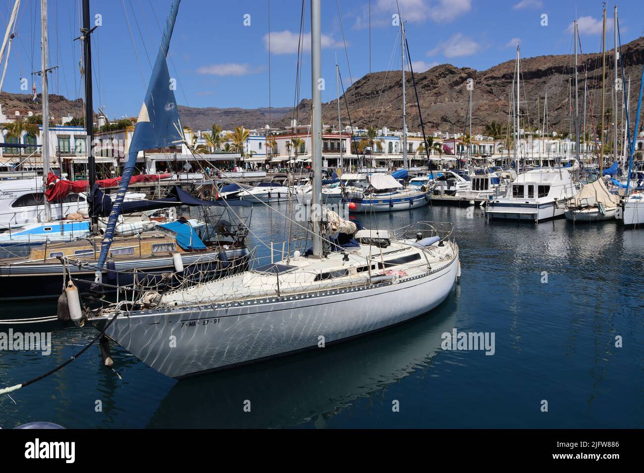 I riflessi della luce del sole, dalle increspature nell'acqua creano un disegno astratto sugli scafi degli yacht nel porticciolo di Playa de Mogan, Gran Canaria Foto Stock