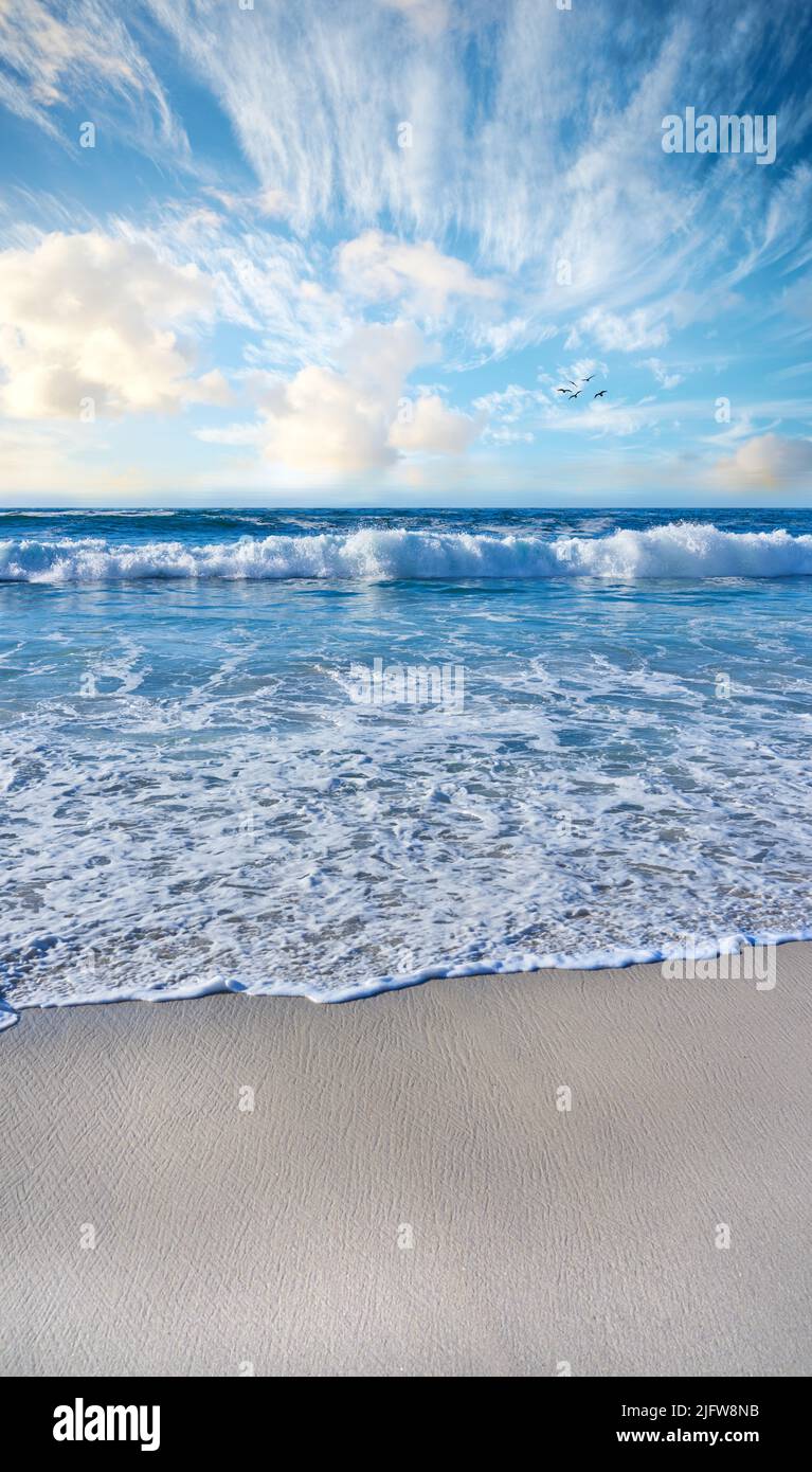 Spiaggia sabbiosa, mare, cielo blu con nuvole e spazio copia. Vista panoramica sul mare delle onde oceaniche che si lavano sulla sabbia in un resort tropicale con copyspace Foto Stock