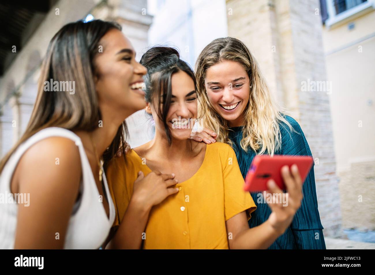 Le giovani donne felici che si divertono insieme a guardare contenuti multimediali divertenti sul telefono Foto Stock